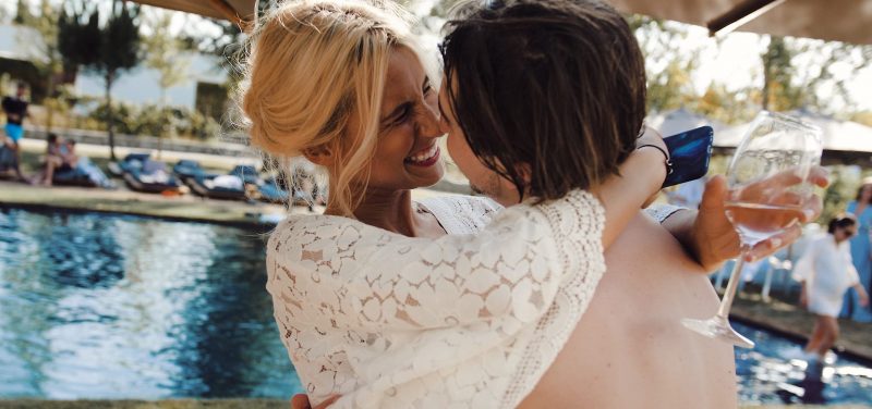 bride and groom embracing next to a pool during their wedding